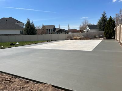 New concrete driveway or patio beside a house in a suburban backyard