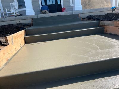 Freshly poured concrete steps and front walkway leading to a house entrance