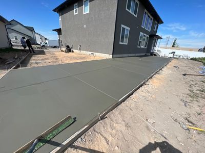 Fresh concrete driveway poured beside a dark gray house in a new subdivision.