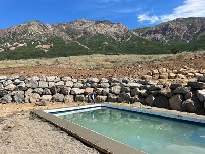 Stone-lined outdoor pool with cloudy water in a rocky mountain landscape