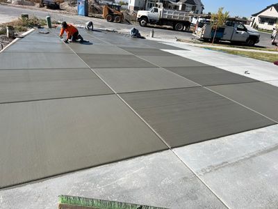 Workers smoothing freshly poured concrete on a driveway slab in a residential construction area