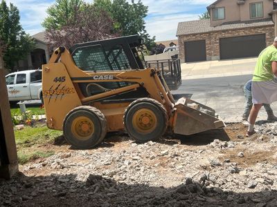 Construction worker using a skid steer to clear rubble in a suburban yard