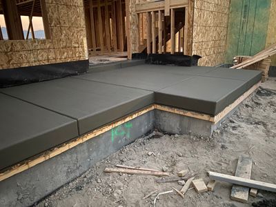 Fresh gray concrete front steps under construction beside a framed house exterior