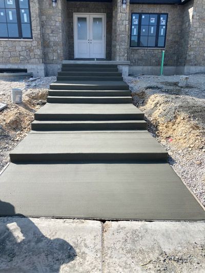 Freshly poured concrete front steps and walkway leading to a house entrance under construction