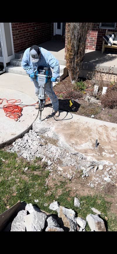 Person in blue jacket working with a small dog on a leash in a sunny front yard