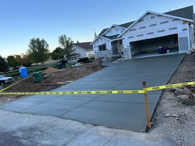 New concrete driveway under construction with caution tape in front of a suburban house.