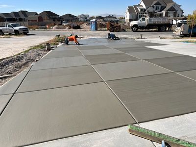 Workers smoothing fresh concrete driveway in a suburban neighborhood under construction