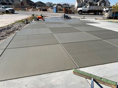 Freshly poured concrete driveway sections at a construction site with workers in the distance