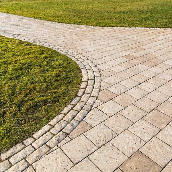 Curved stone walkway bordered by green grass in a park