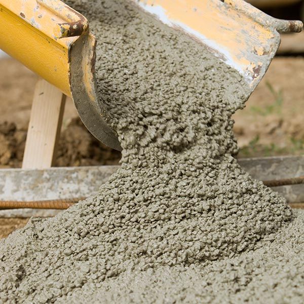 Wet concrete pouring from a yellow mixer chute onto a construction site