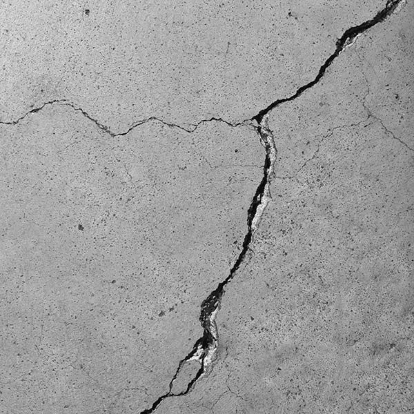 Cracked gray concrete surface with a large jagged fracture