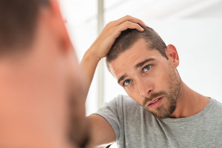 Mann fährt sich besorgt durch Haare