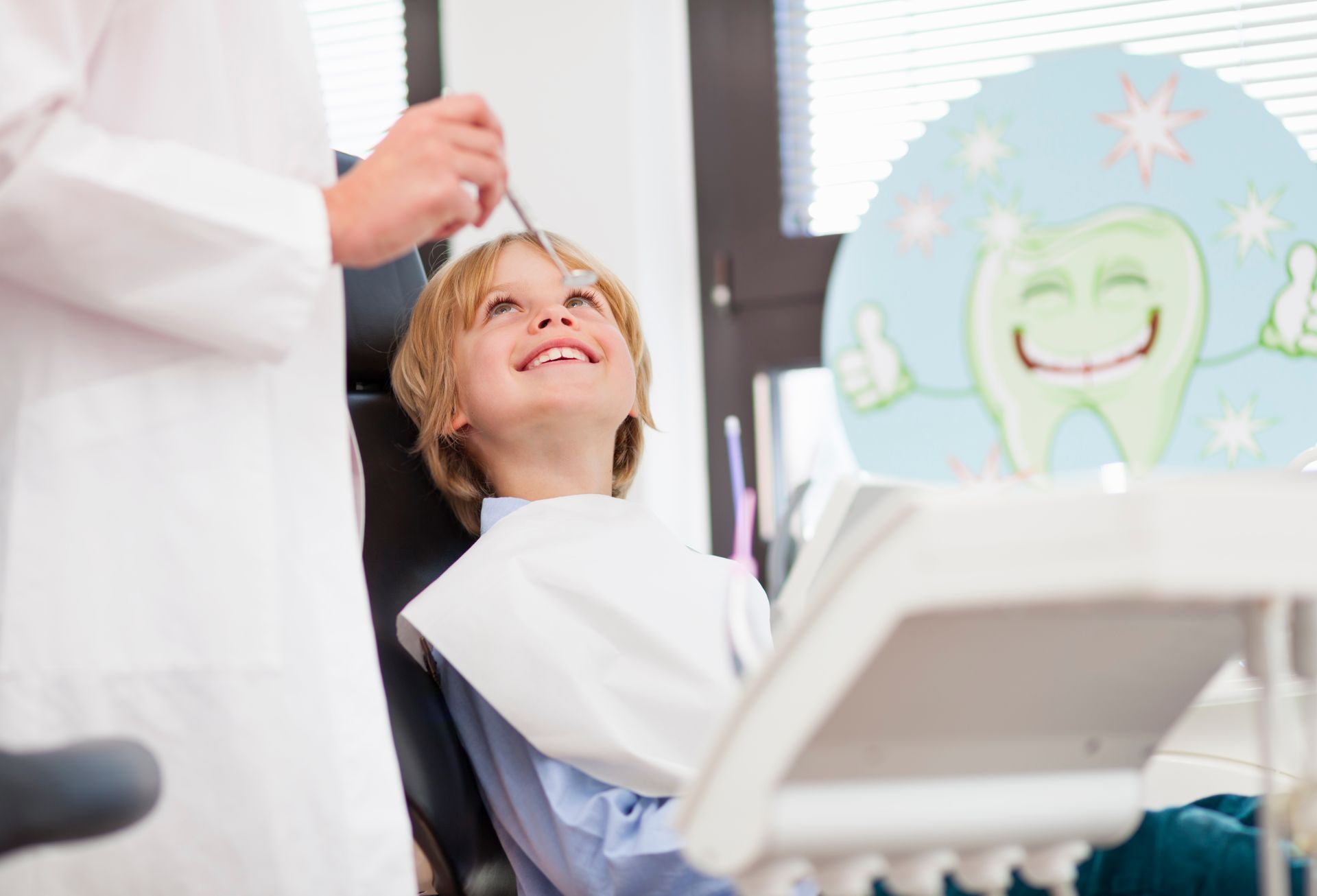 Un ragazzino è seduto sulla poltrona del dentista mentre un dentista gli esamina i denti.