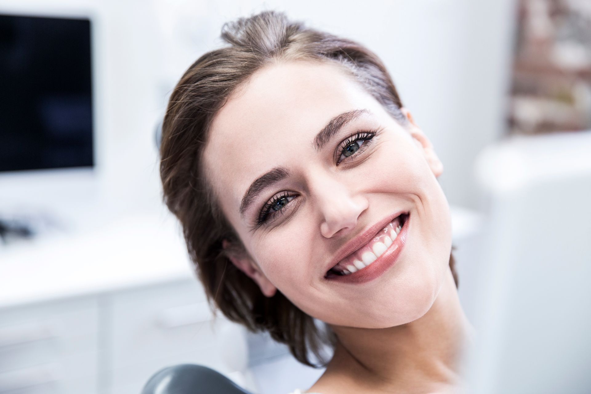 Una donna sorride mentre è seduta sulla poltrona del dentista.