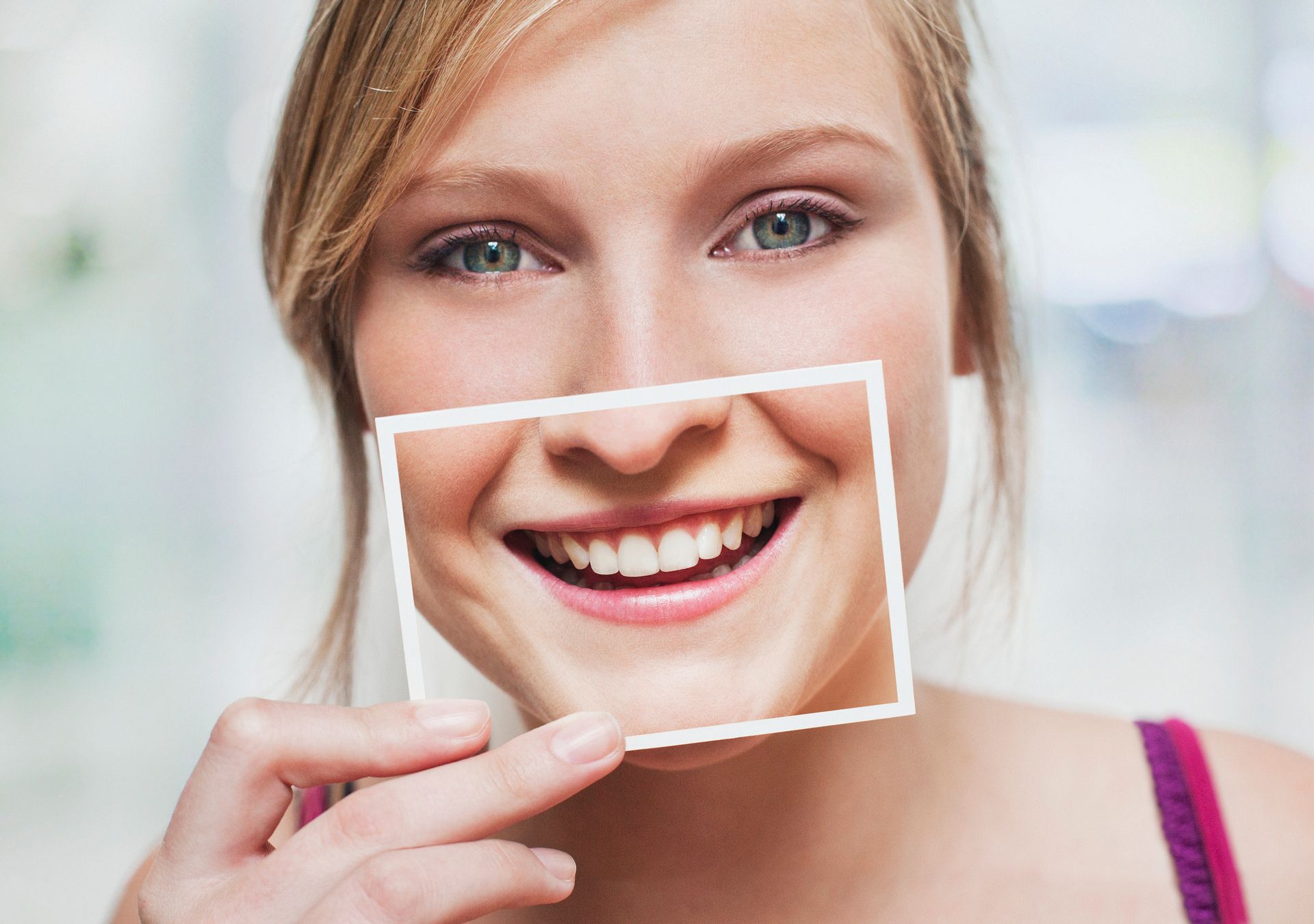 Una donna tiene davanti al viso la foto del suo sorriso.