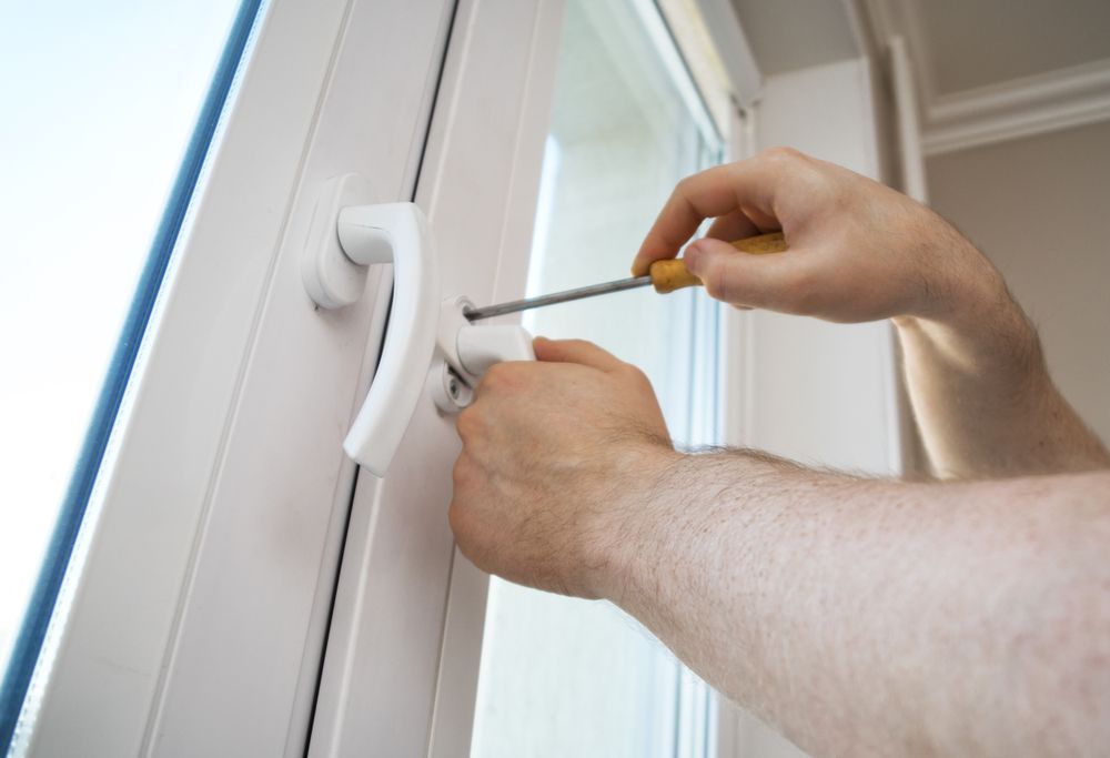 A Man Is Fixing A Window Handle With A Screwdriver — Roo’s Door & Window Maintenance In Sippy Downs, QLD