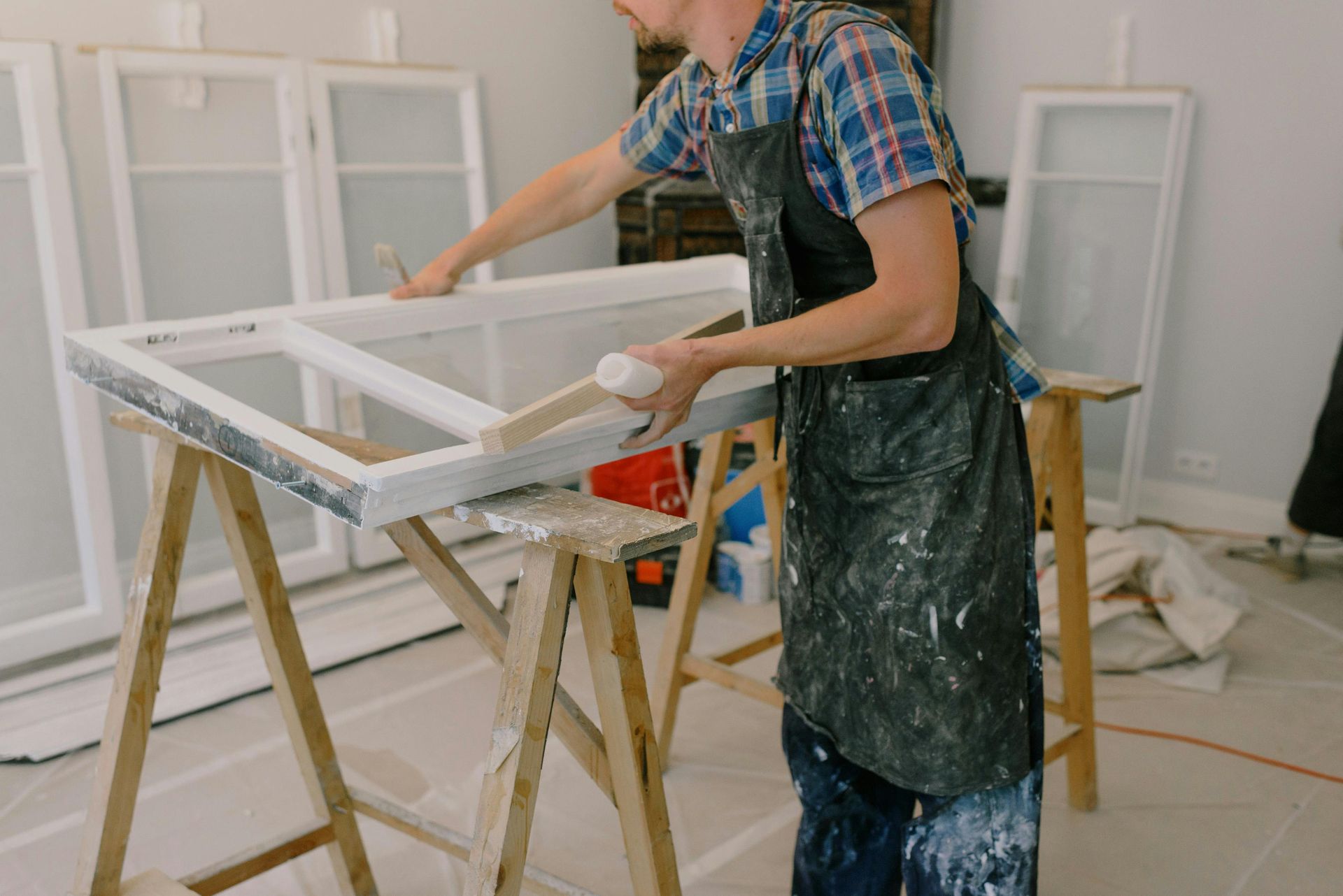 A Man Is Painting A Window Frame In A Room — Roo’s Door & Window Maintenance In Sippy Downs