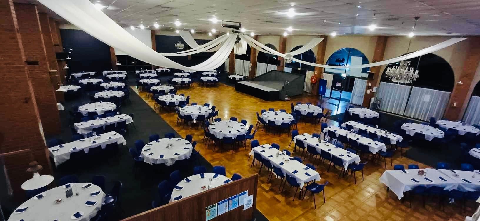 A large room with tables and chairs set up for a wedding reception