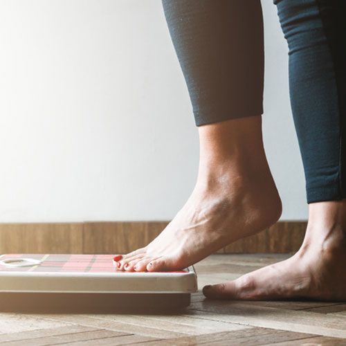 Female checking kilogrammes getting on the scale