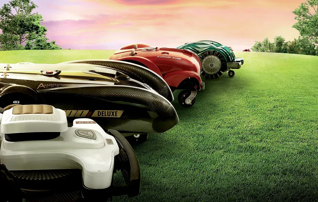 Lawnmowers lined up on a grassy field, racing towards the horizon. Red, green, black and white mowers in front of a colorful sky.