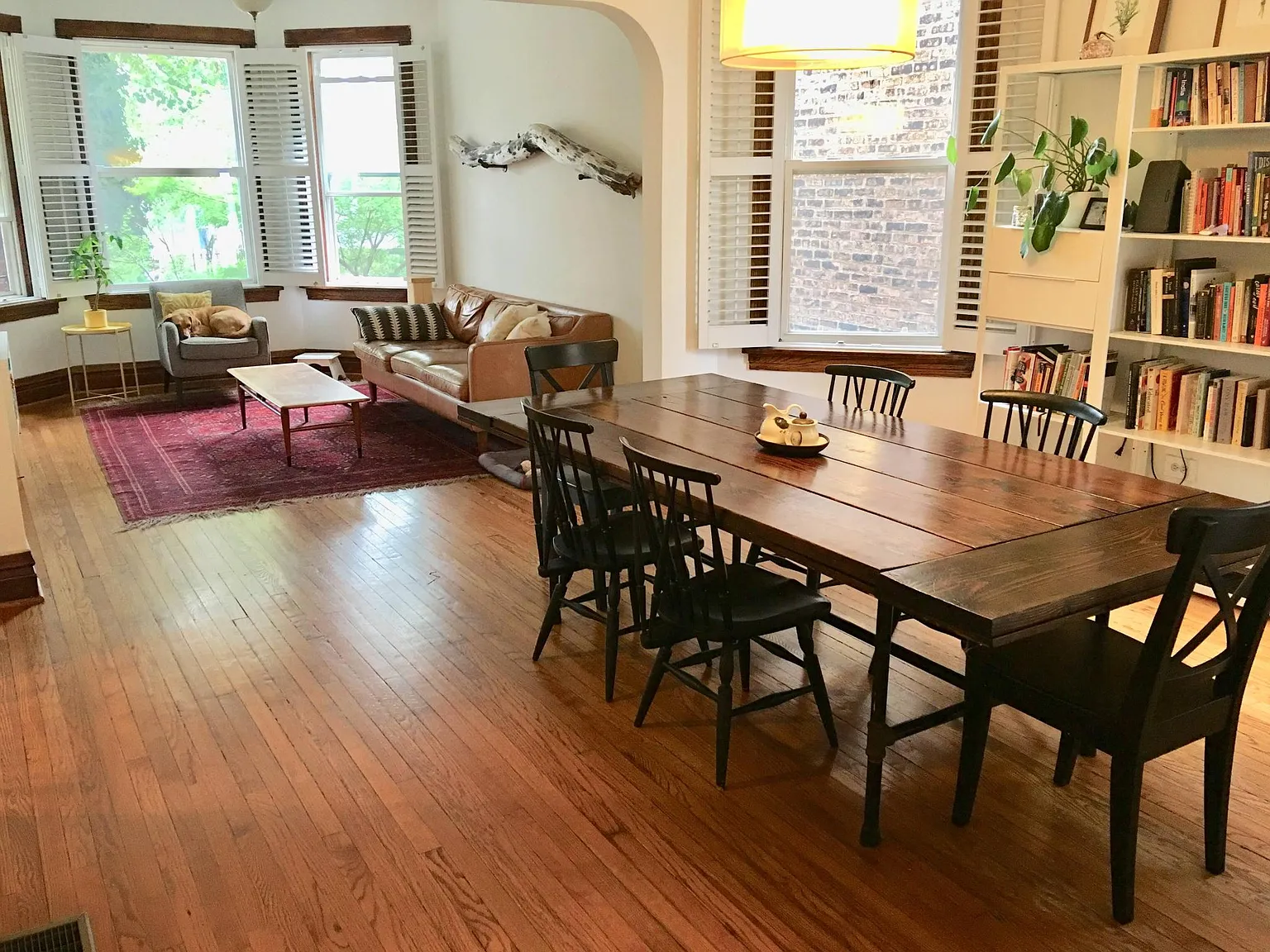 Living room with wooden floors, dining table, and built-in bookshelves.