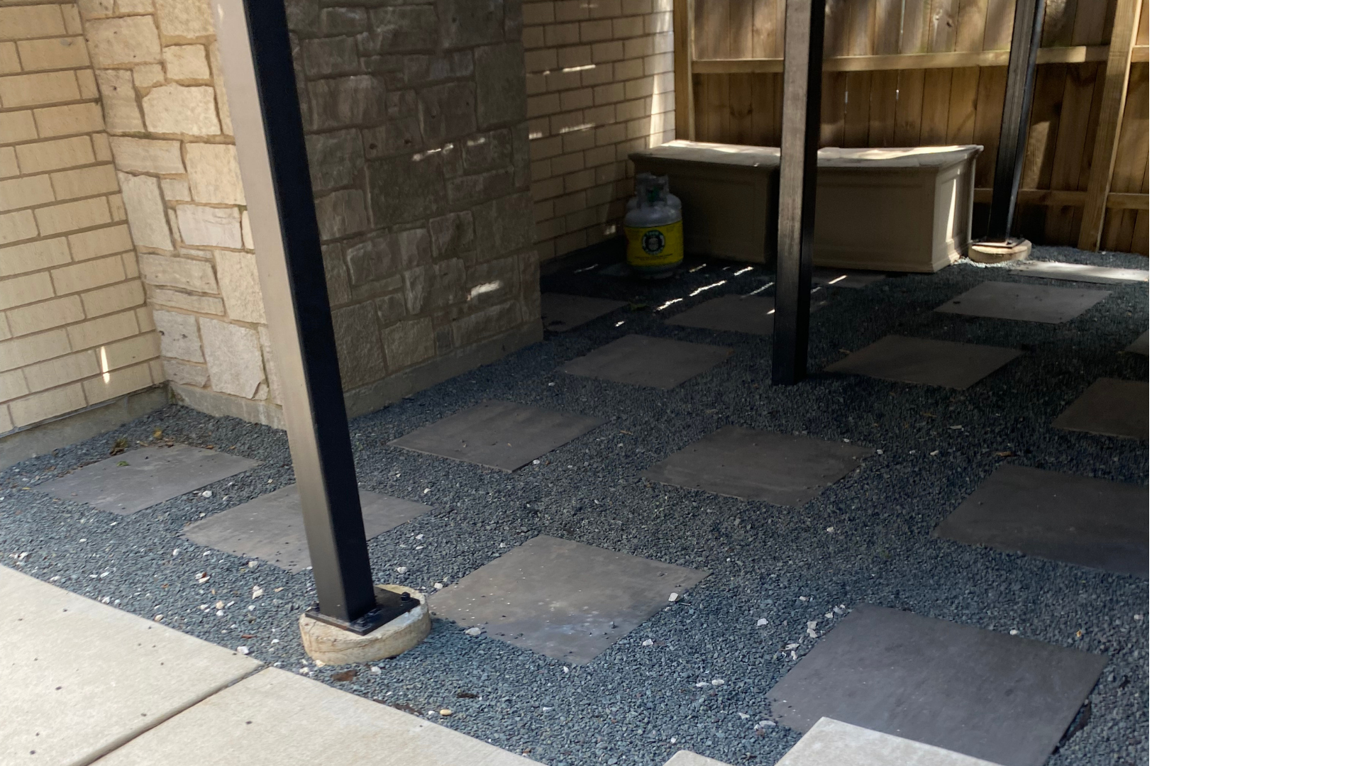 Patio with stepping stones, gravel, and a stone wall. A hot tub is in the background.