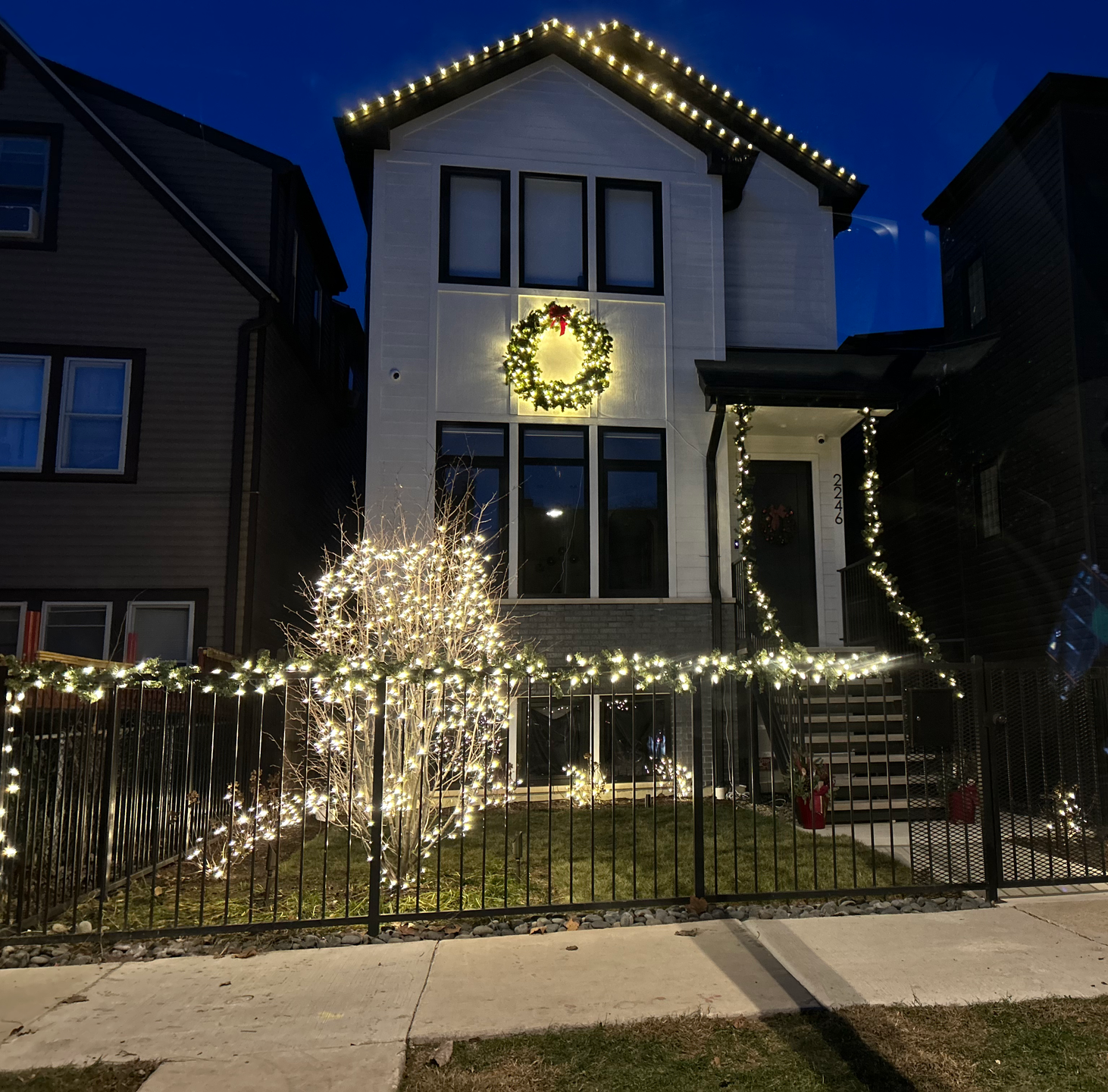 White house decorated with Christmas lights and wreath.