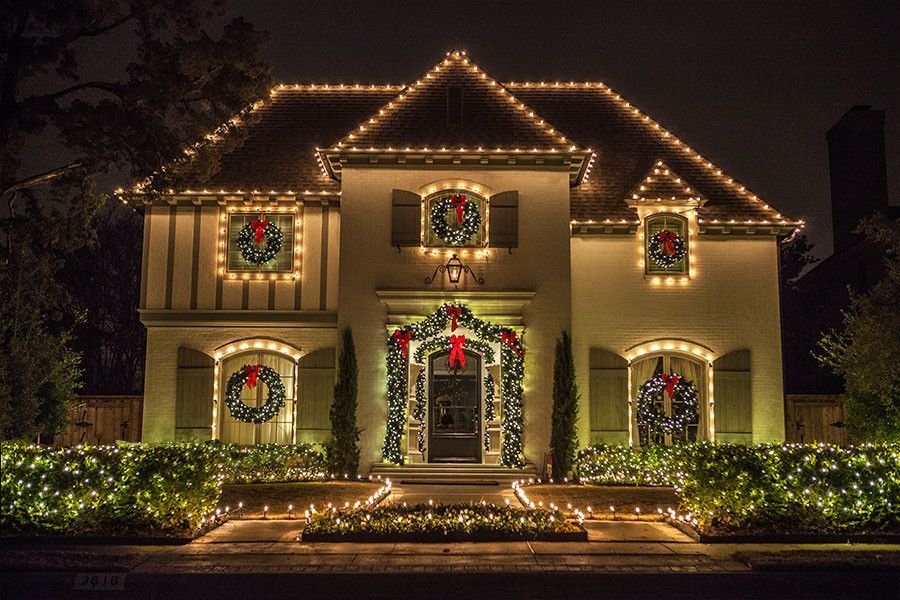 House lit with Christmas lights and wreaths; nighttime scene.