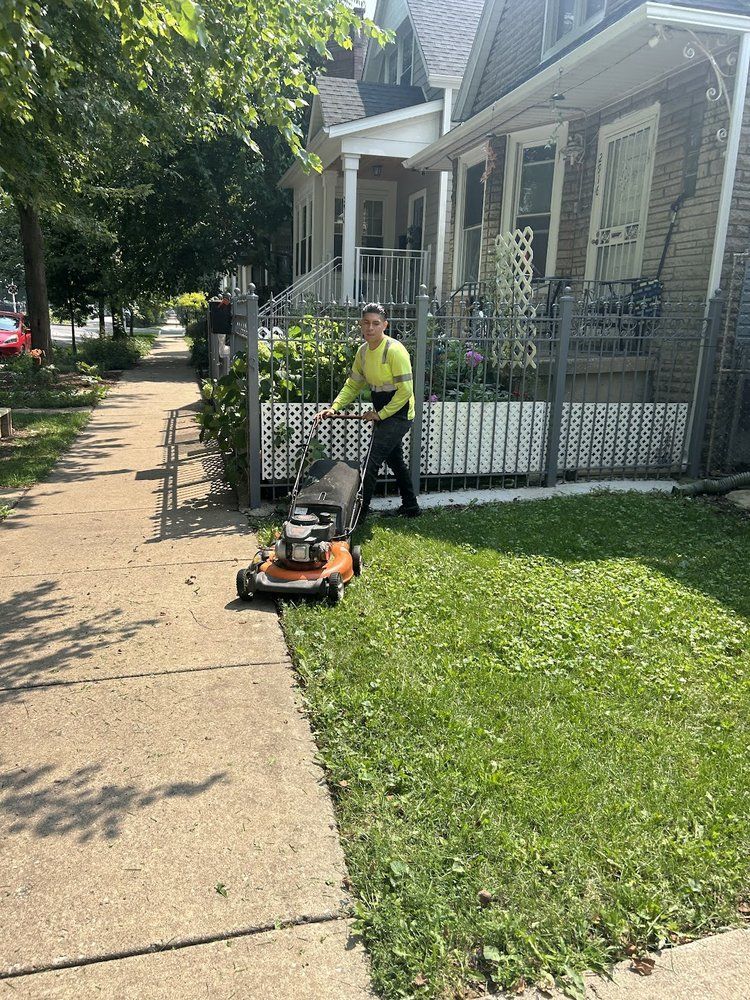 Person mowing lawn with orange lawnmower next to sidewalk, in front of a house.