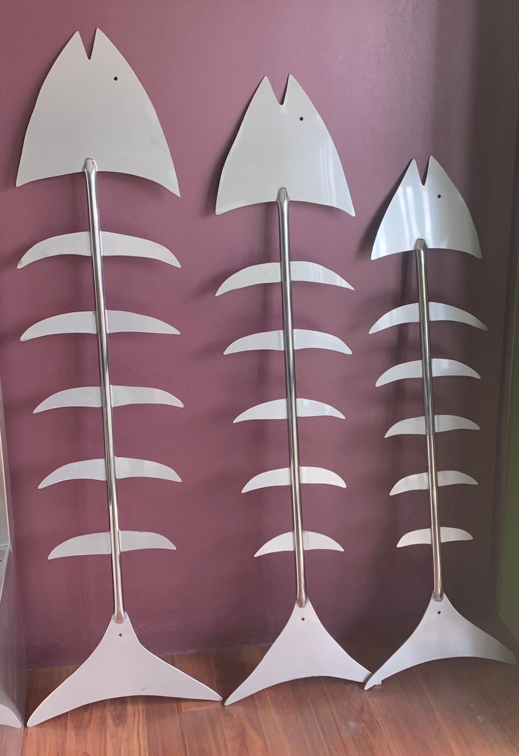 Three metal fish skeleton decorations on a red wall — Metaltrendz in Kunda Park, QLD