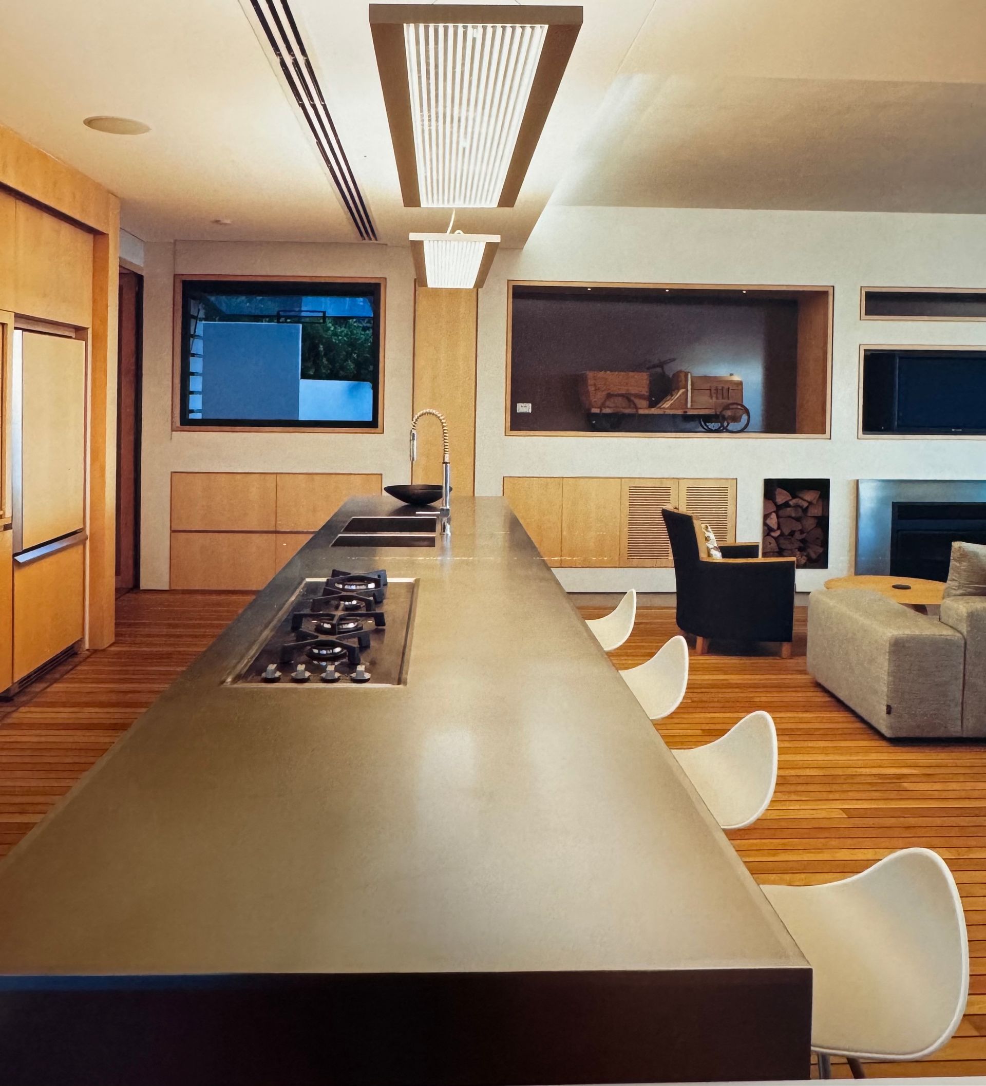Modern kitchen with long island, built-in cooktop, and white chairs — Metaltrendz in Kunda Park, QLD