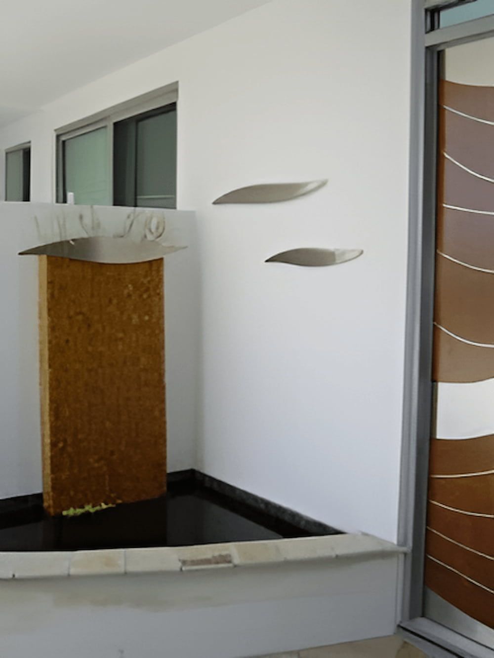 Water fountain with a stone column, wall art, and a patterned brown door — Metaltrendz in Kunda Park, QLD