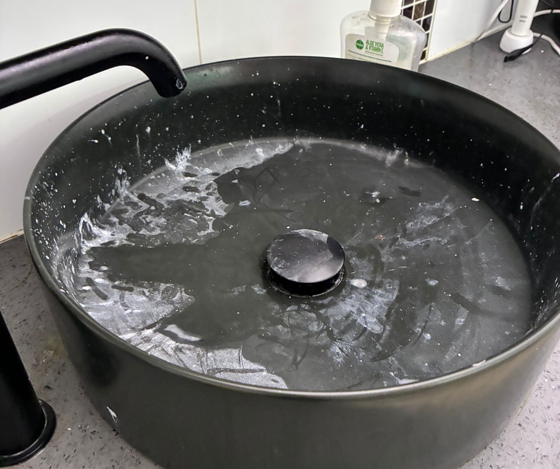 Black Sink Basin With Water Swirls — Schmucker Cleaning in Gulliver, QLD