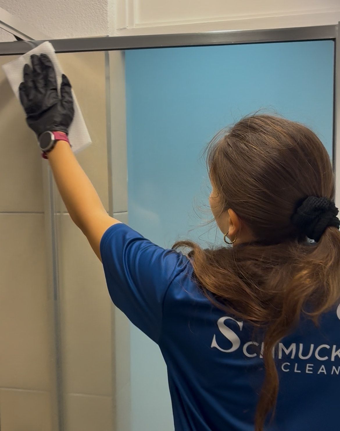 An Employee Wiping Down a Shower Screen — Schmucker Cleaning in Gulliver, QLD