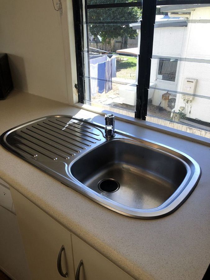 A Kitchen Sink with A Window in The Background — Schmucker Cleaning in Gulliver, QLD