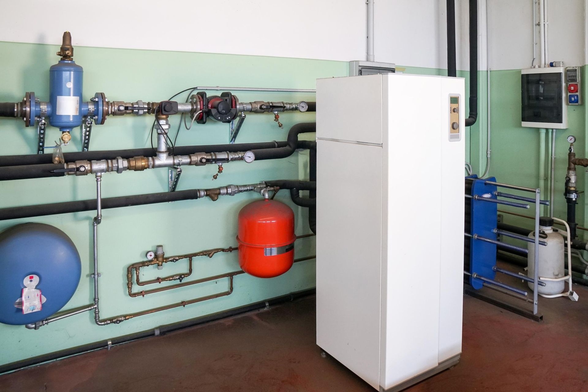 Water heater and piping in an industrial setting, with tanks, valves, and a control panel.