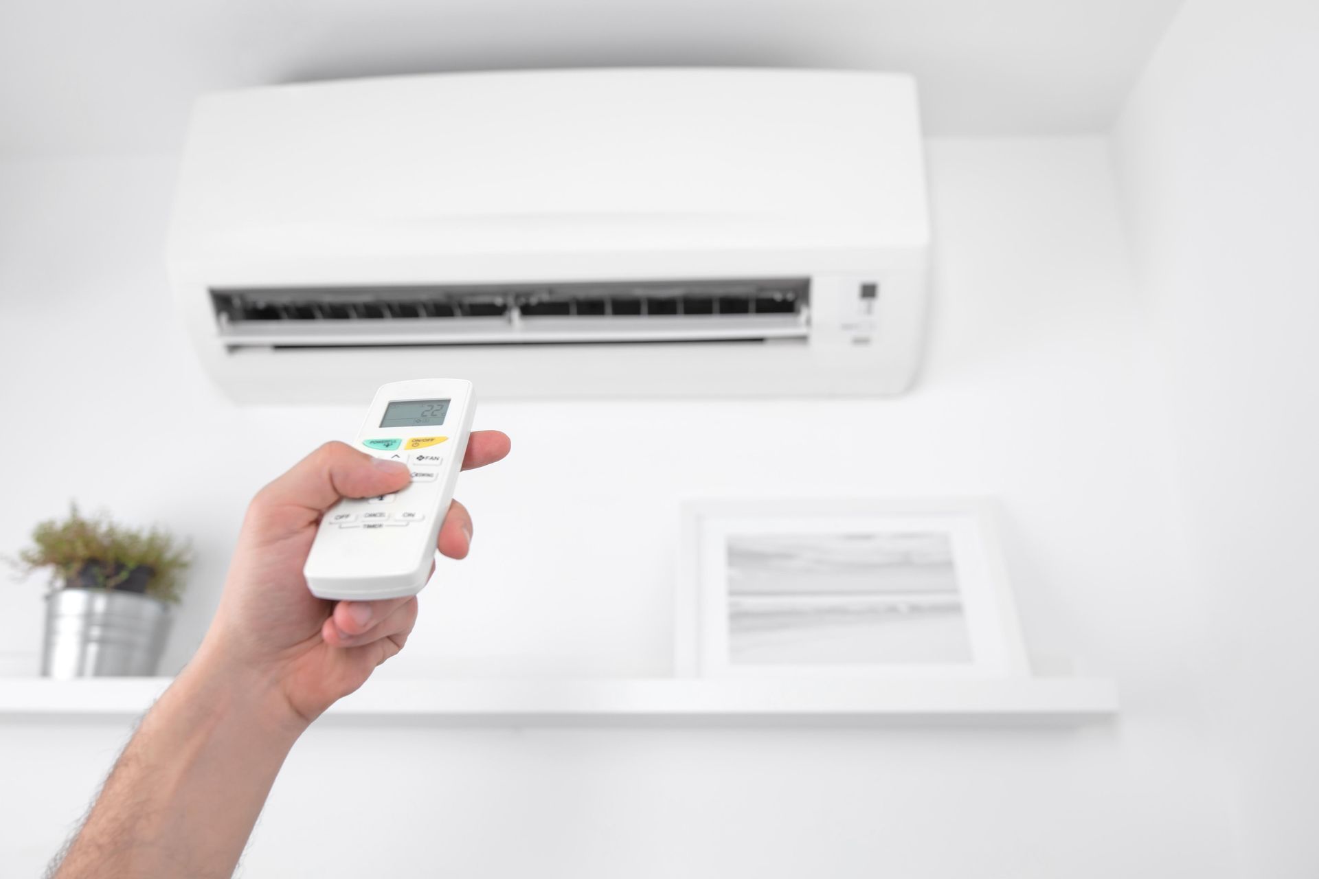 Hand operating an air conditioner's remote. 