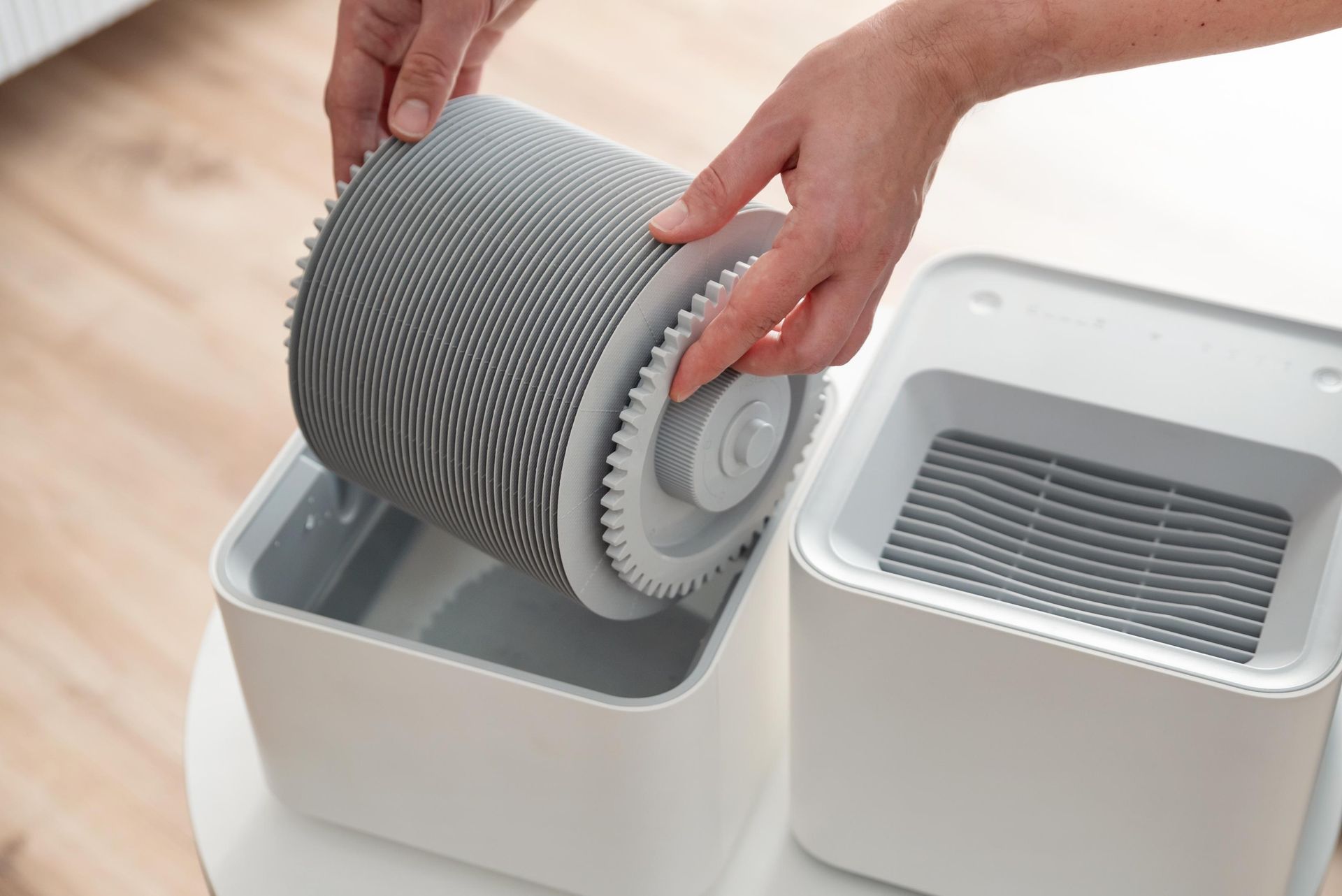 Hands placing a gray, textured roller into a white container; another container is beside it.
