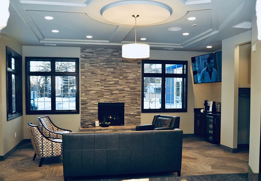 Modern lobby with sofa, chairs, fireplace, and large windows under a coffered ceiling
