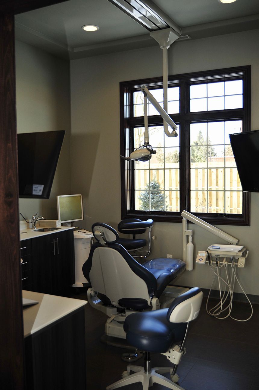 Dental exam room with blue chair, overhead light, and large window in the background