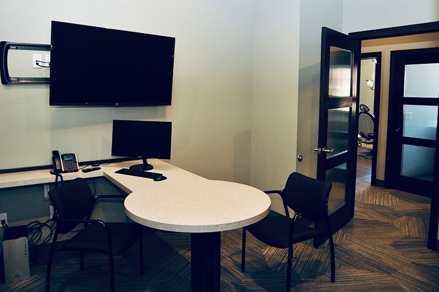 Modern office with white desks, black chairs, and wall-mounted monitors near a glass door