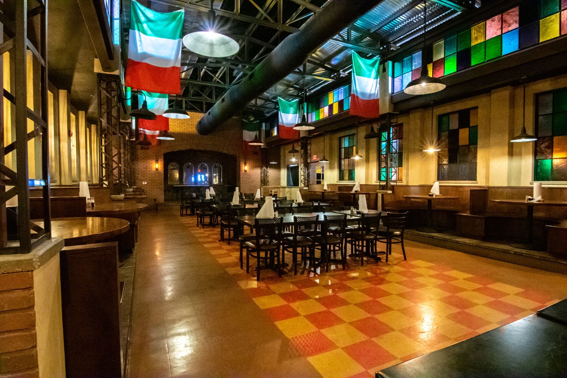 A restaurant with tables and chairs and flags hanging from the ceiling.