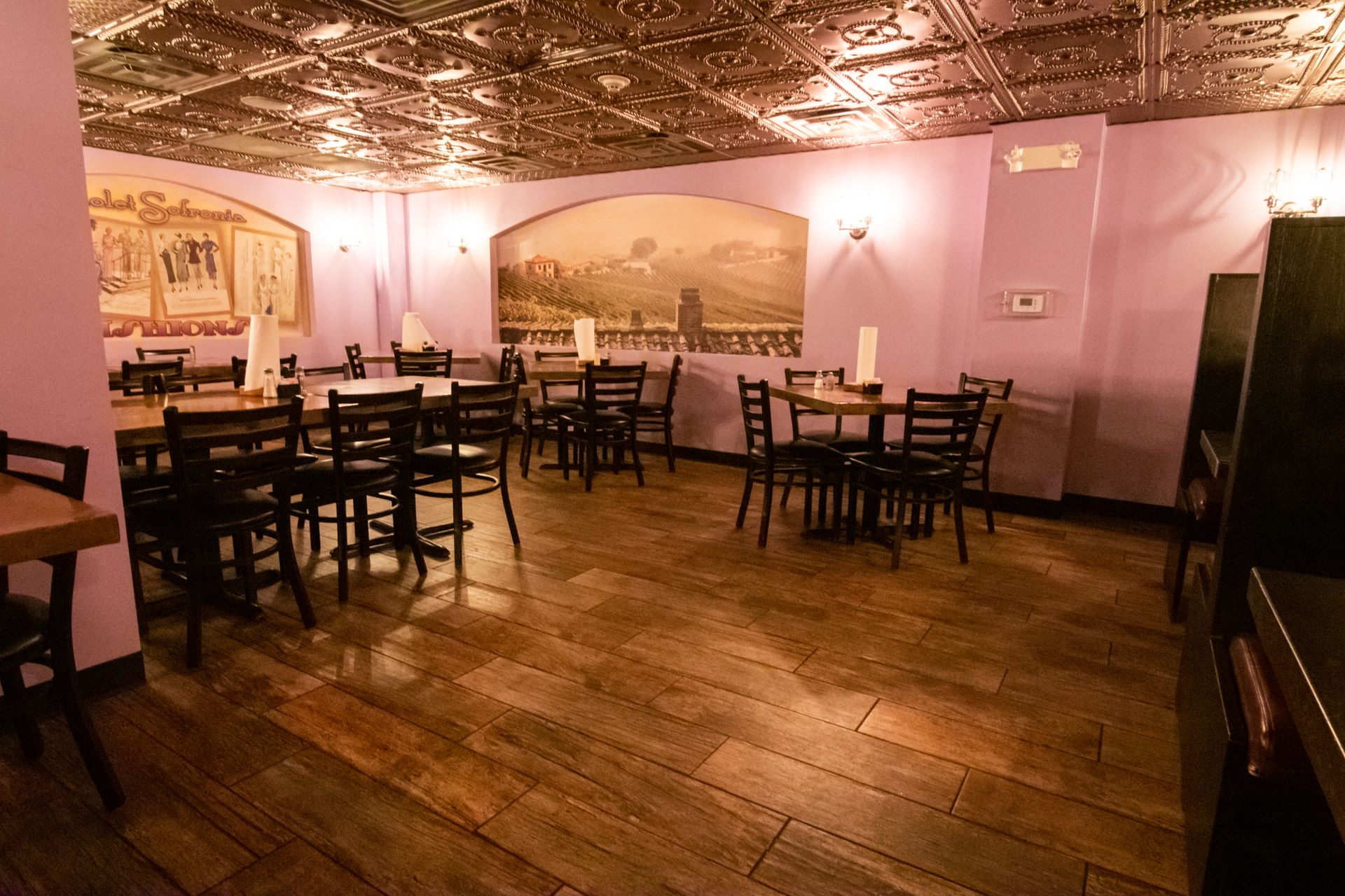 A restaurant with tables and chairs and a purple ceiling.