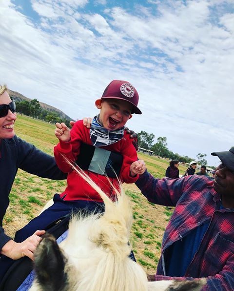 Smiling Little Boy on Horse Held by two pair of Hands — Blatherskite Park in Alice Springs, NT