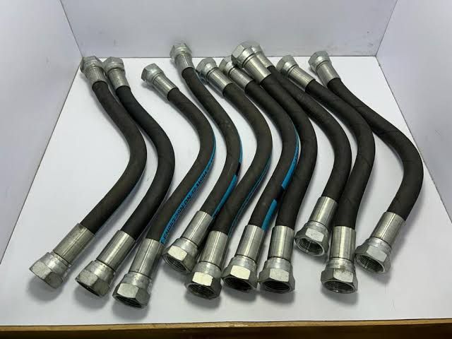 Several black flexible hoses with silver metal fittings arranged in a white box