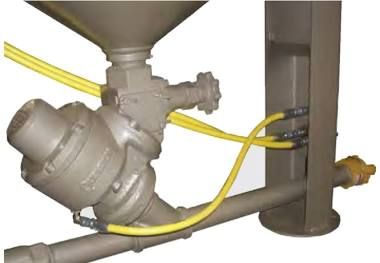 Industrial pipe valve assembly with yellow hoses connected to a metal tank and piping system