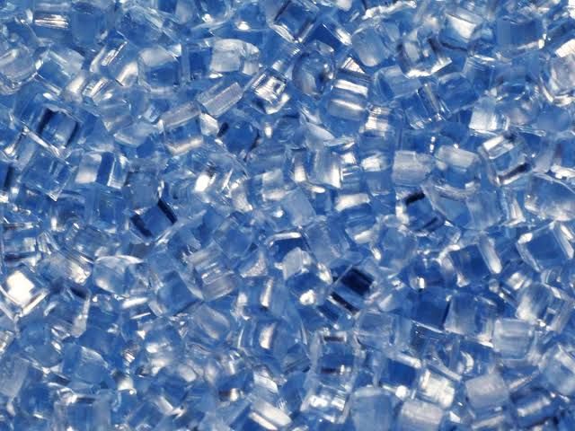 Pile of small translucent blue plastic pellets scattered across a surface