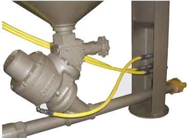 Industrial machinery with yellow hoses connected to a metal pipe assembly and vertical tank