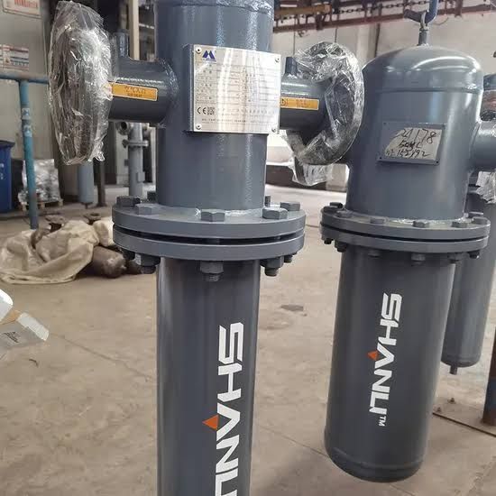 Two gray industrial SHANNI filter units standing on a factory floor, wrapped parts visible in the background