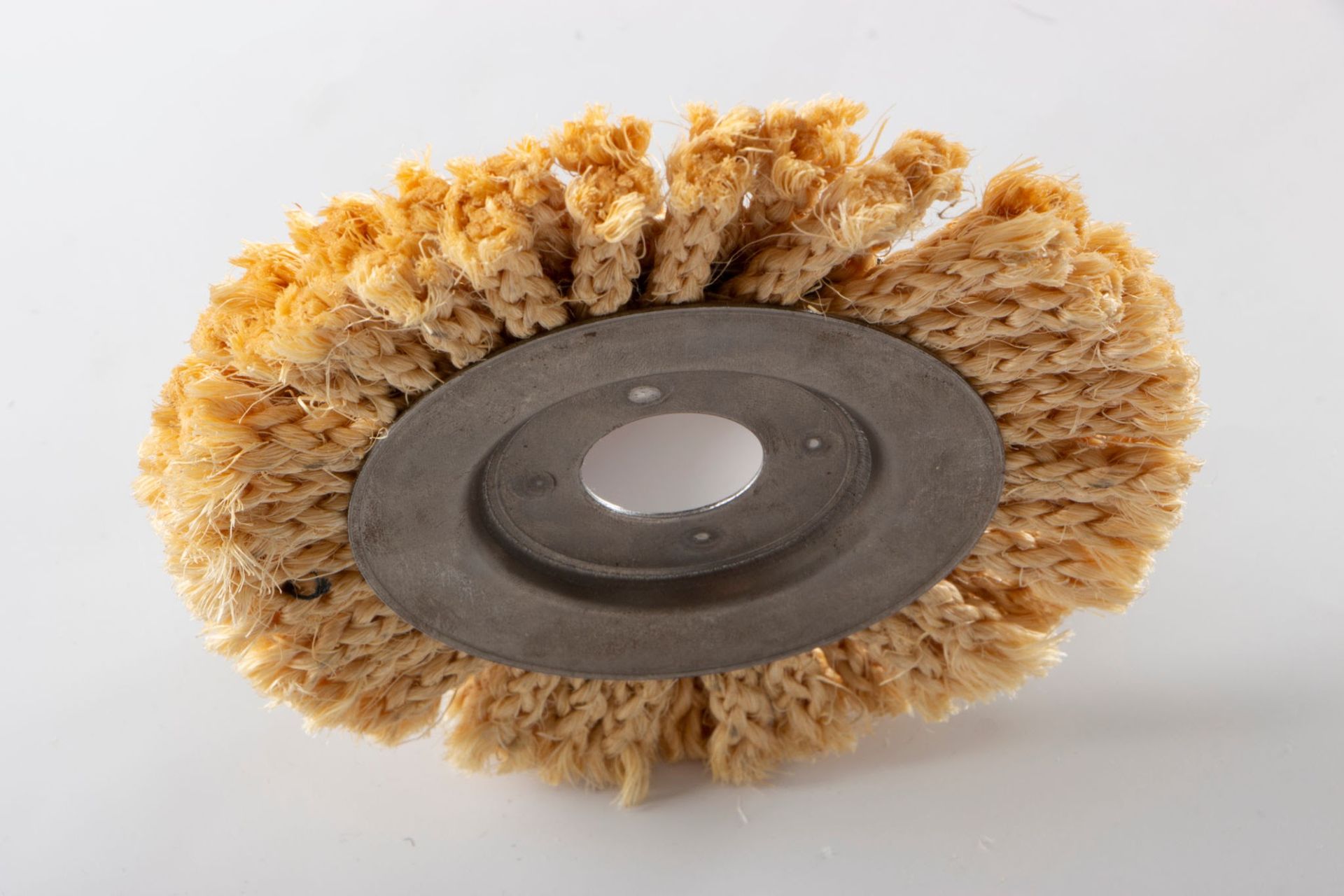 Round wire brush wheel with tan bristles and a metal center on a white background